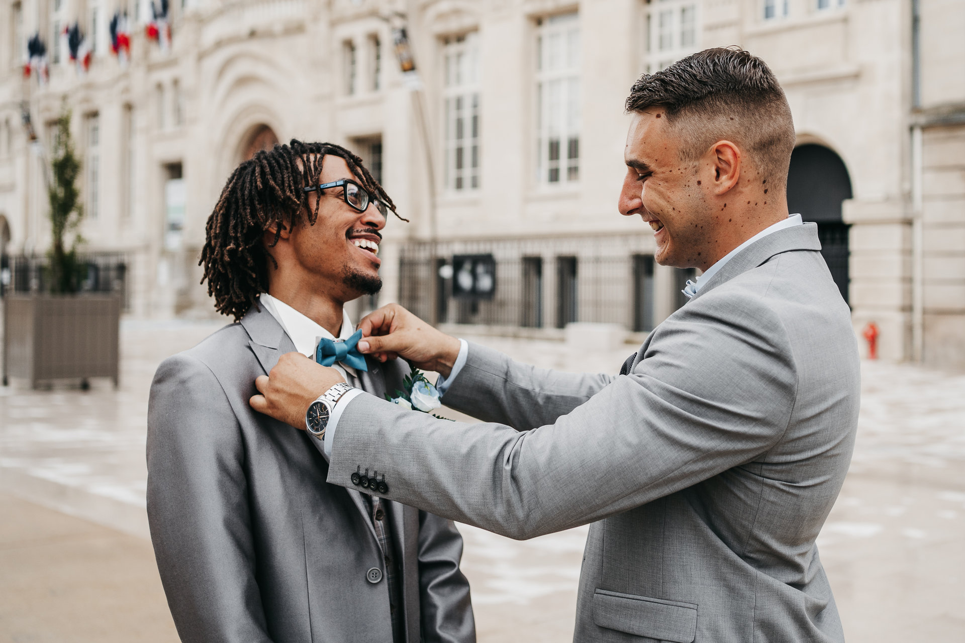 Un homme en costume ajuste la cravate d'un autre homme.