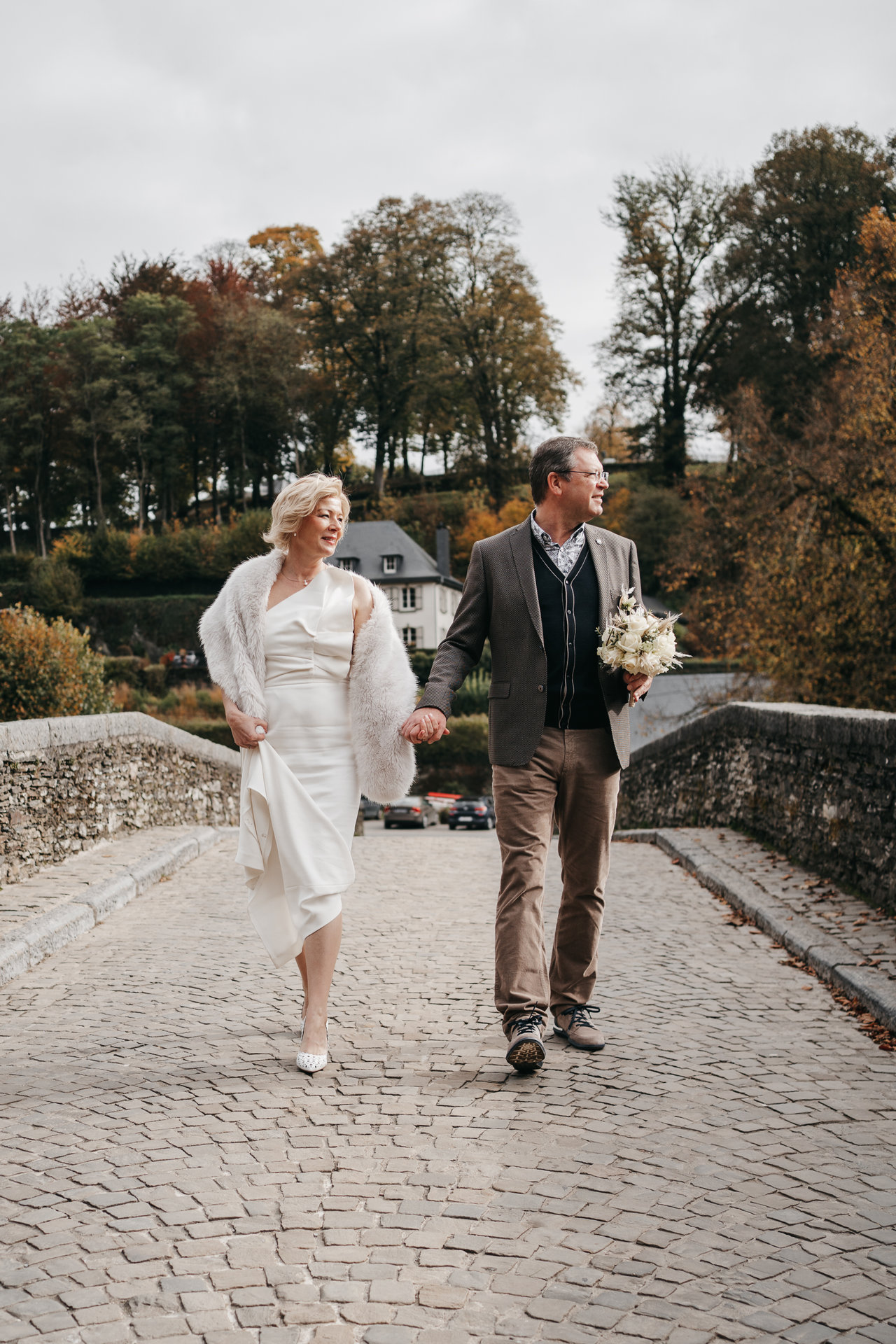 Une mariée et un marié marchant sur un pont de pierre.