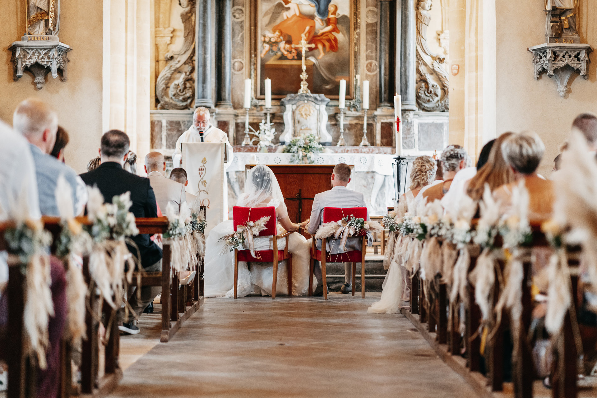 Une cérémonie de mariage dans une église avec des gens assis sur les bancs.