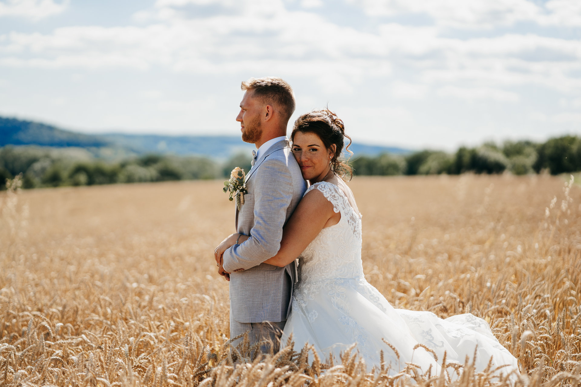 Une mariée et un marié debout dans un champ de blé.