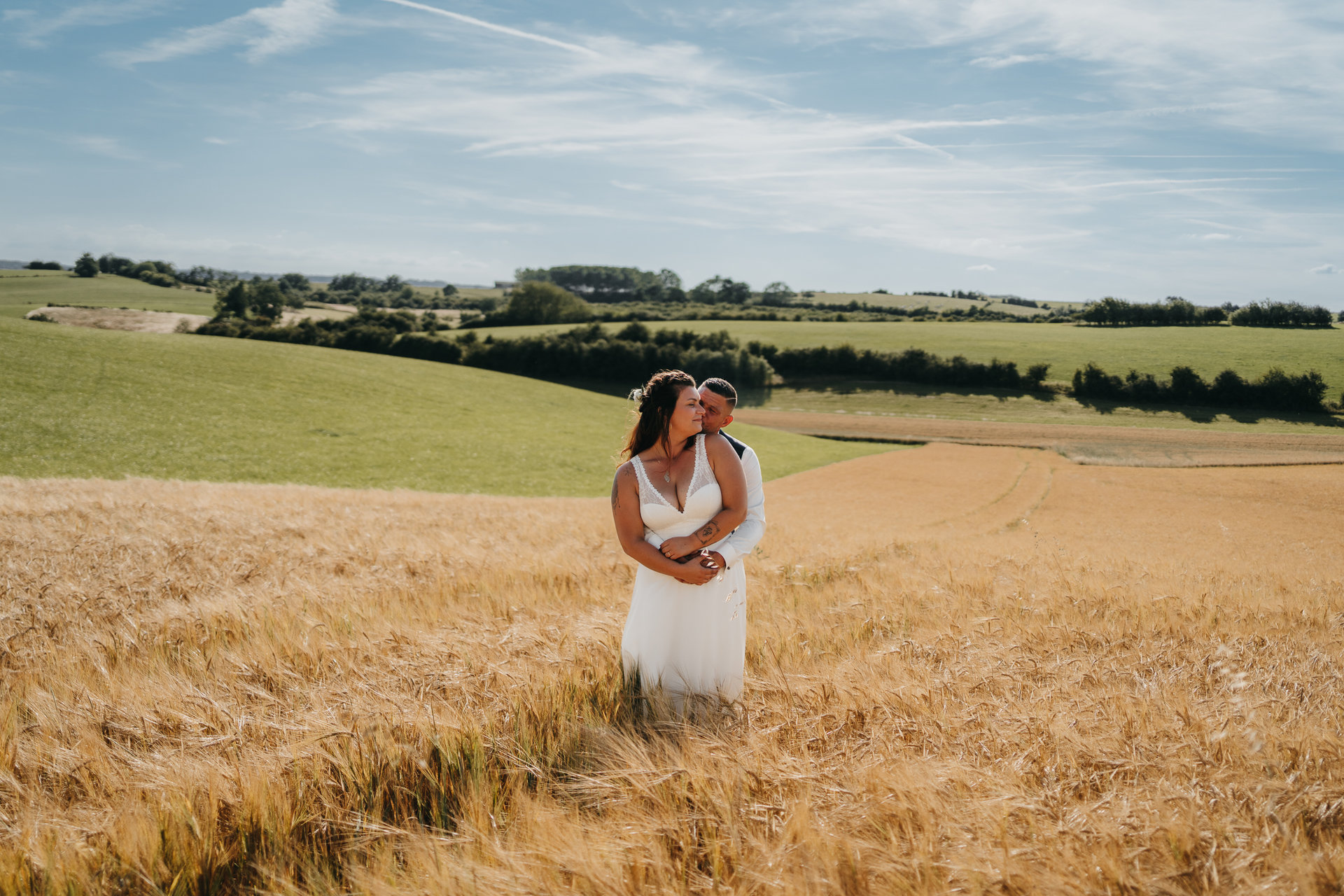Une mariée et un marié debout dans un champ de blé.