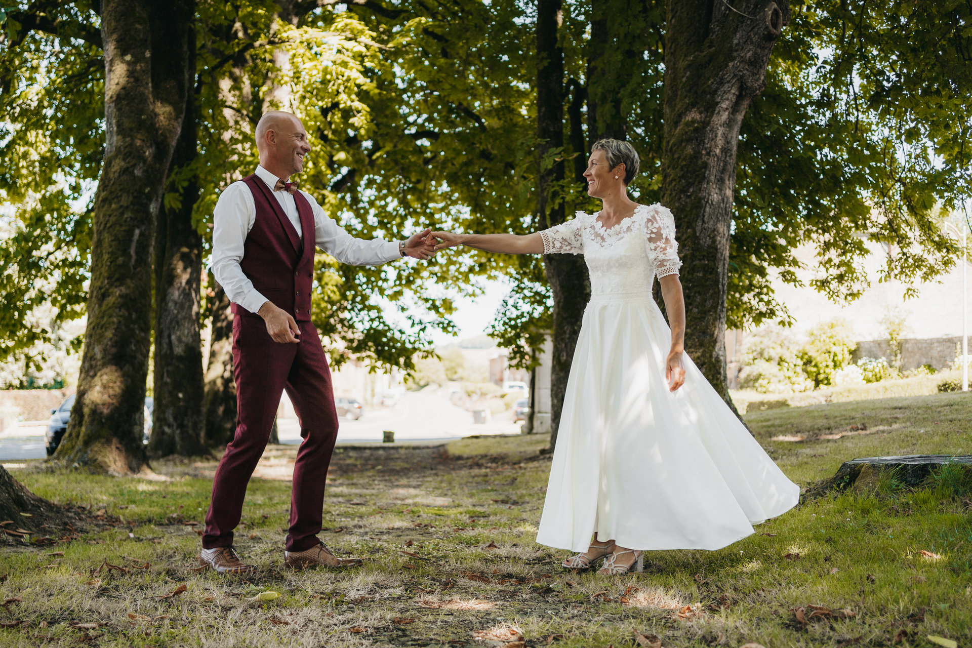 Une mariée et un marié se tenant la main dans un parc.
