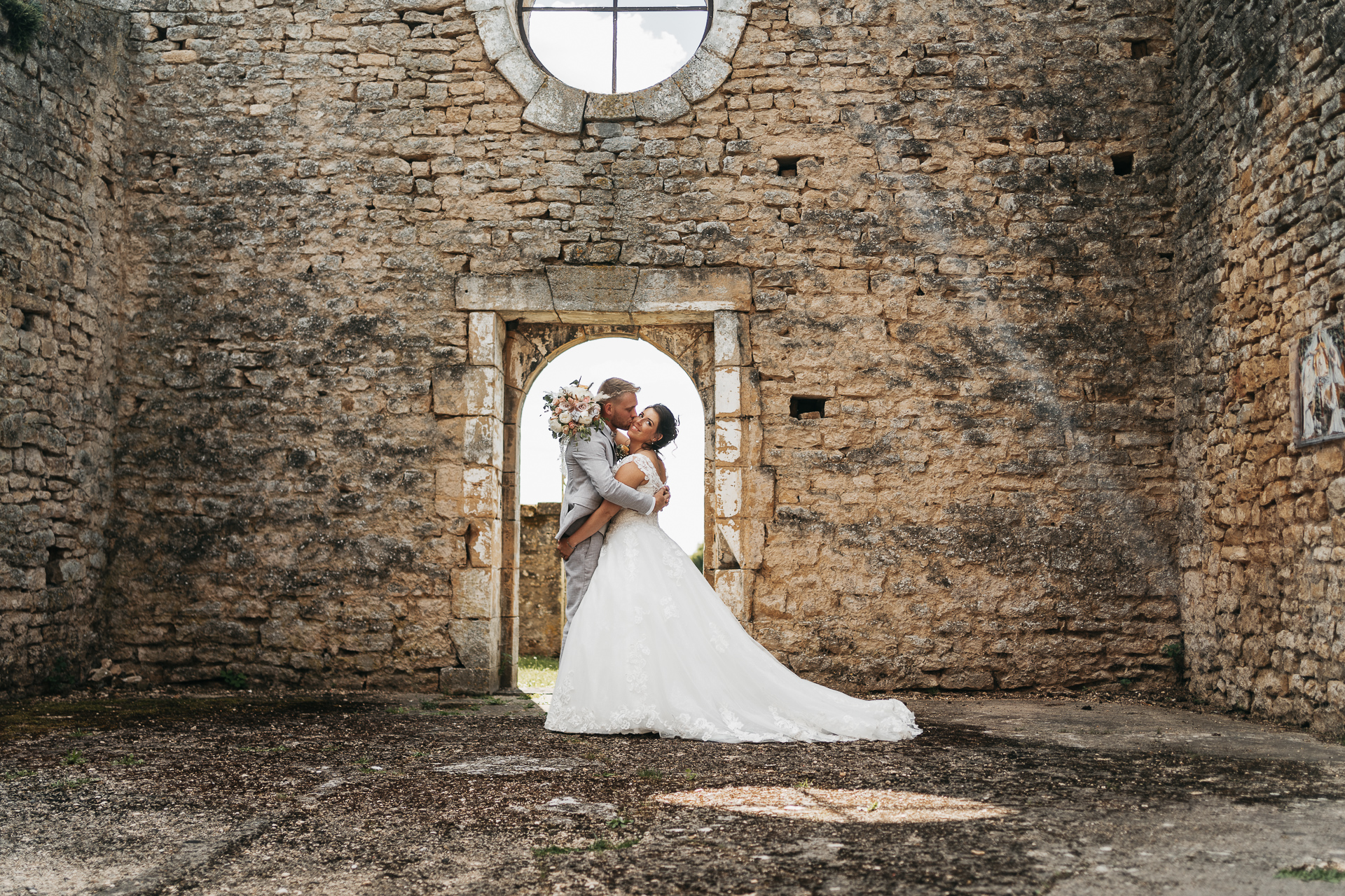 Une mariée et un marié s'embrassant dans un vieux bâtiment en pierre.