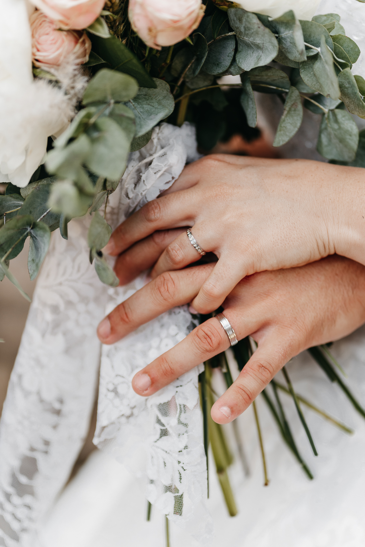 Les mains d'une mariée et d'un marié tenant un bouquet de fleurs.