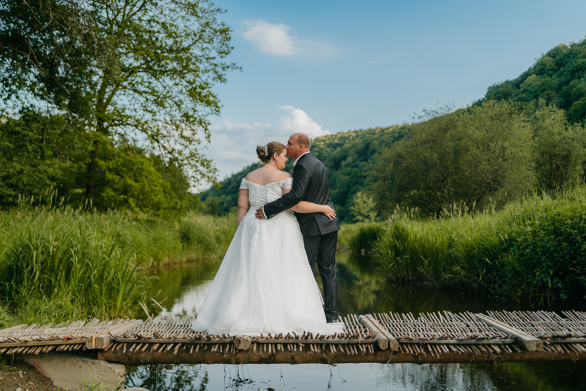 Un photographe capturant un mariage sur un pont en bois au-dessus d'une rivière.