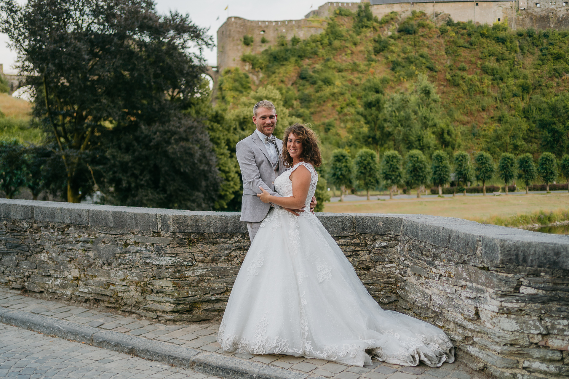 Un couple se faisant photographier sur un pont près d'un château par un photographe professionnel.