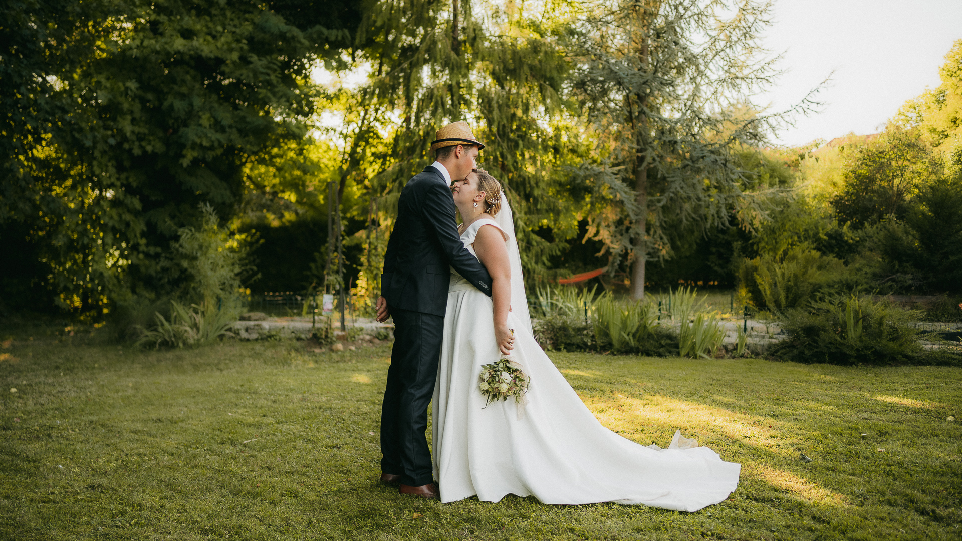 Mots-clés : mariagedescription : Un couple s'embrassant dans un jardin capturé par un photographe de mariage.