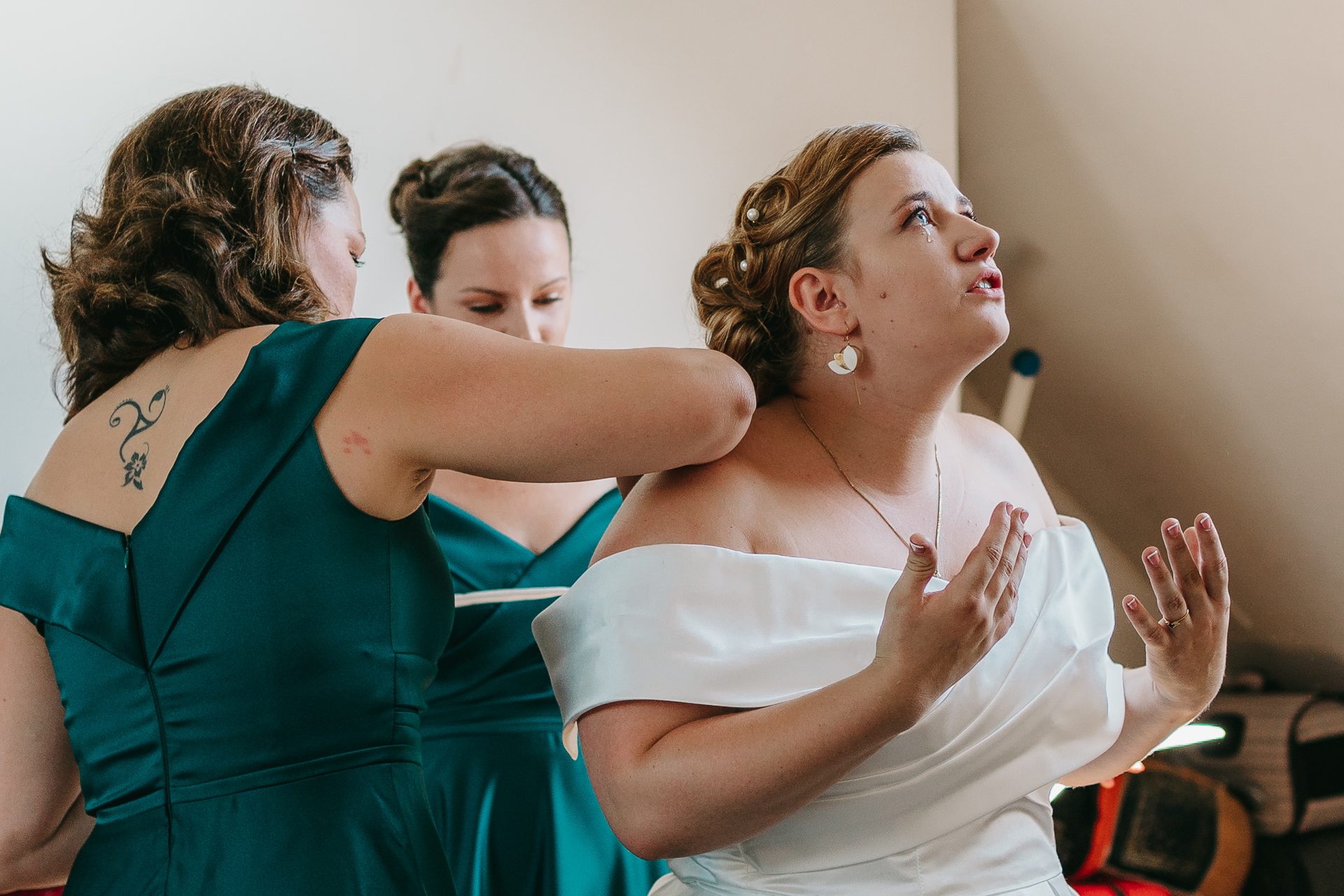 Deux demoiselles d'honneur s'entraident avec leurs robes lors d'un mariage de photographe.