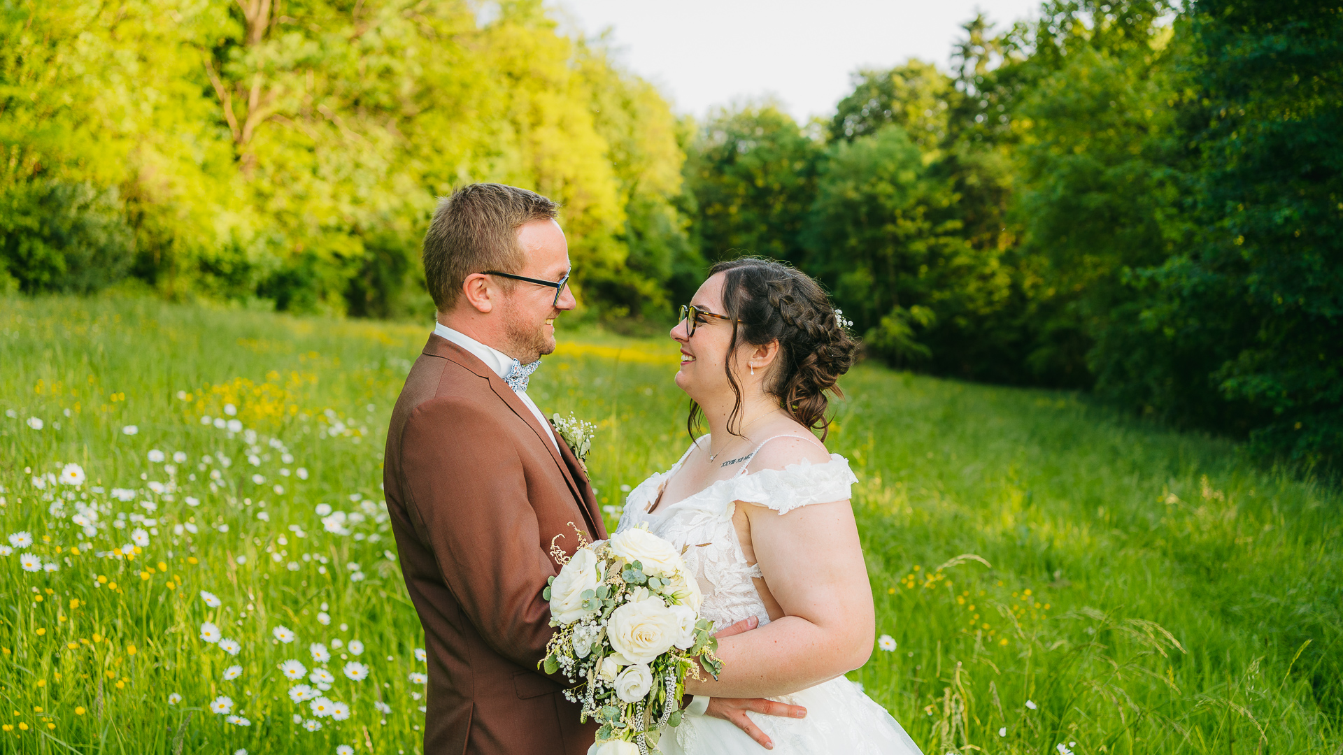 Une mariée et un marié debout dans un champ de marguerites.