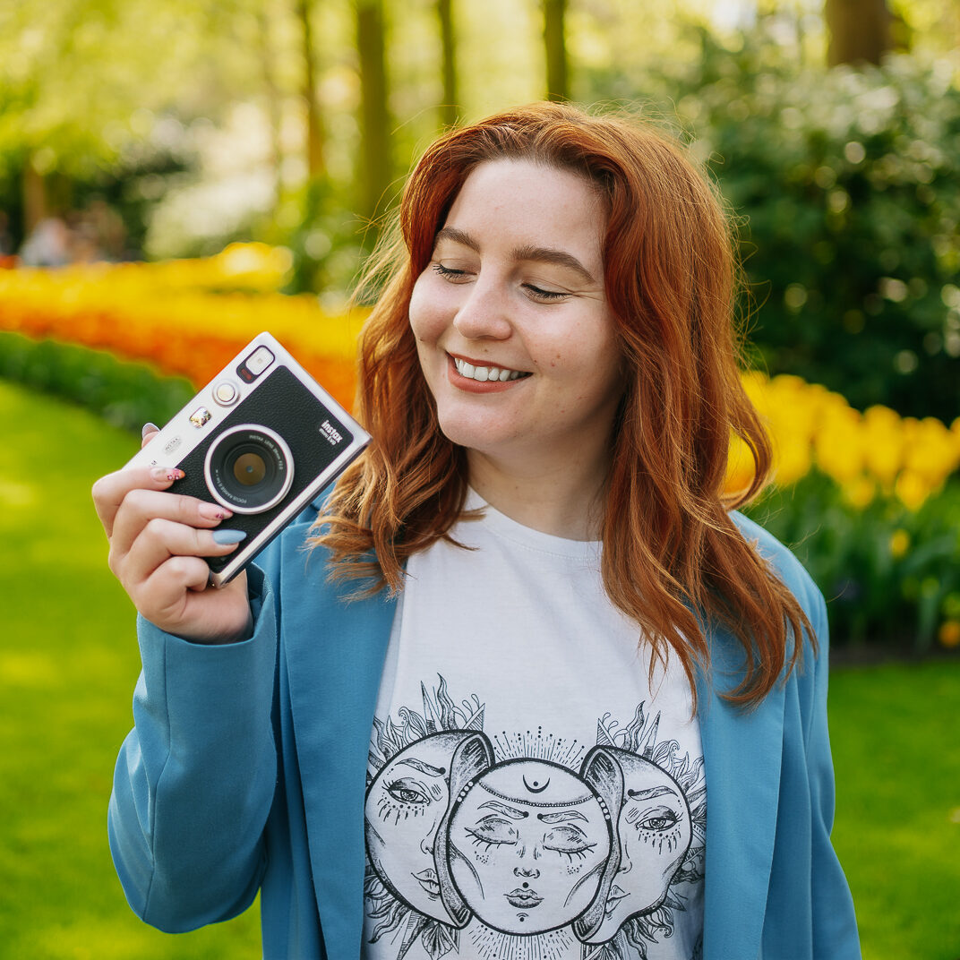 Une femme tenant un appareil photo dans un parc.