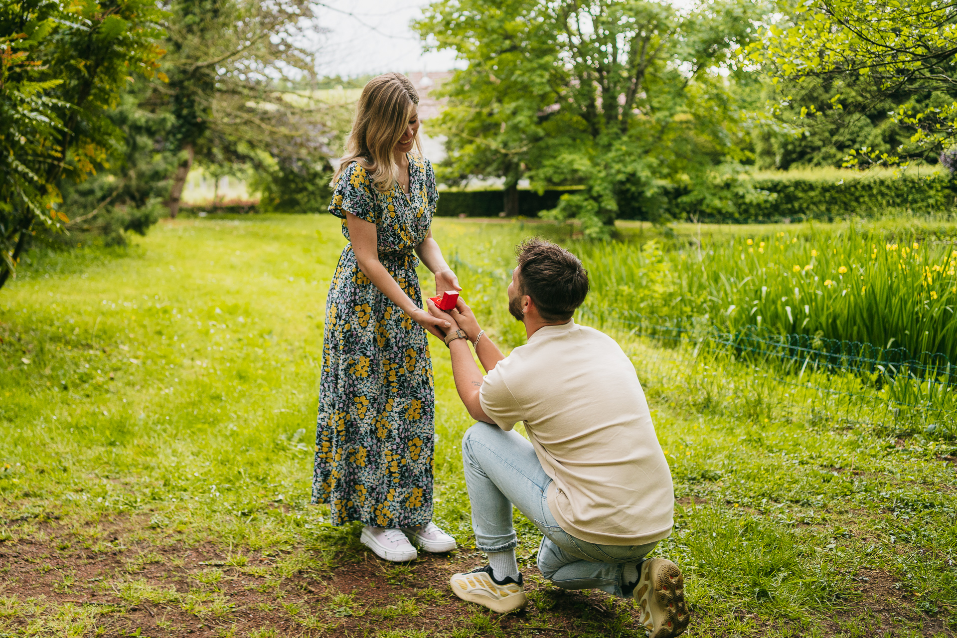 Un homme s'agenouillant pour proposer à une femme dans un champ.