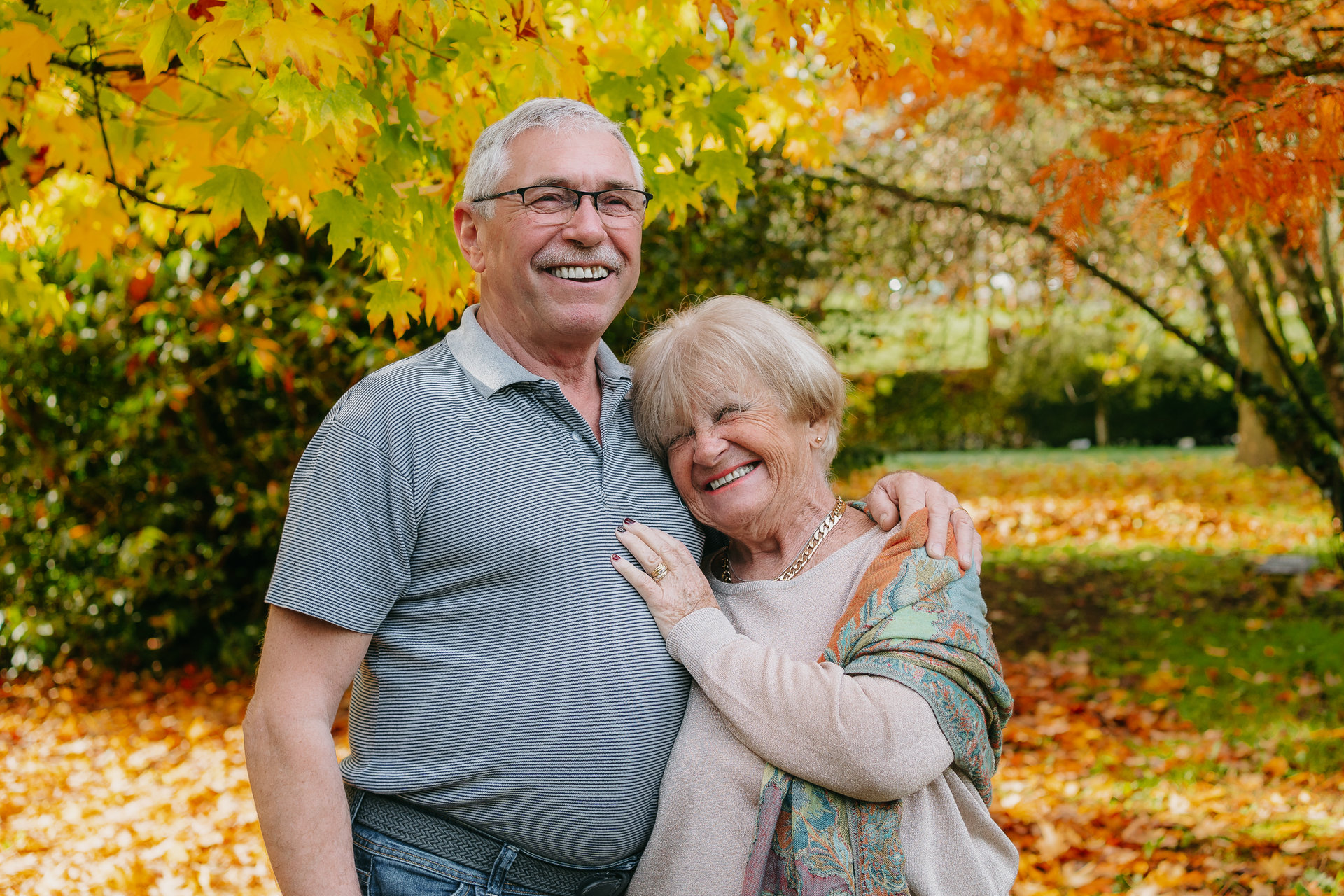 Un couple plus âgé s'embrassant dans un parc avec des feuilles d'automne.