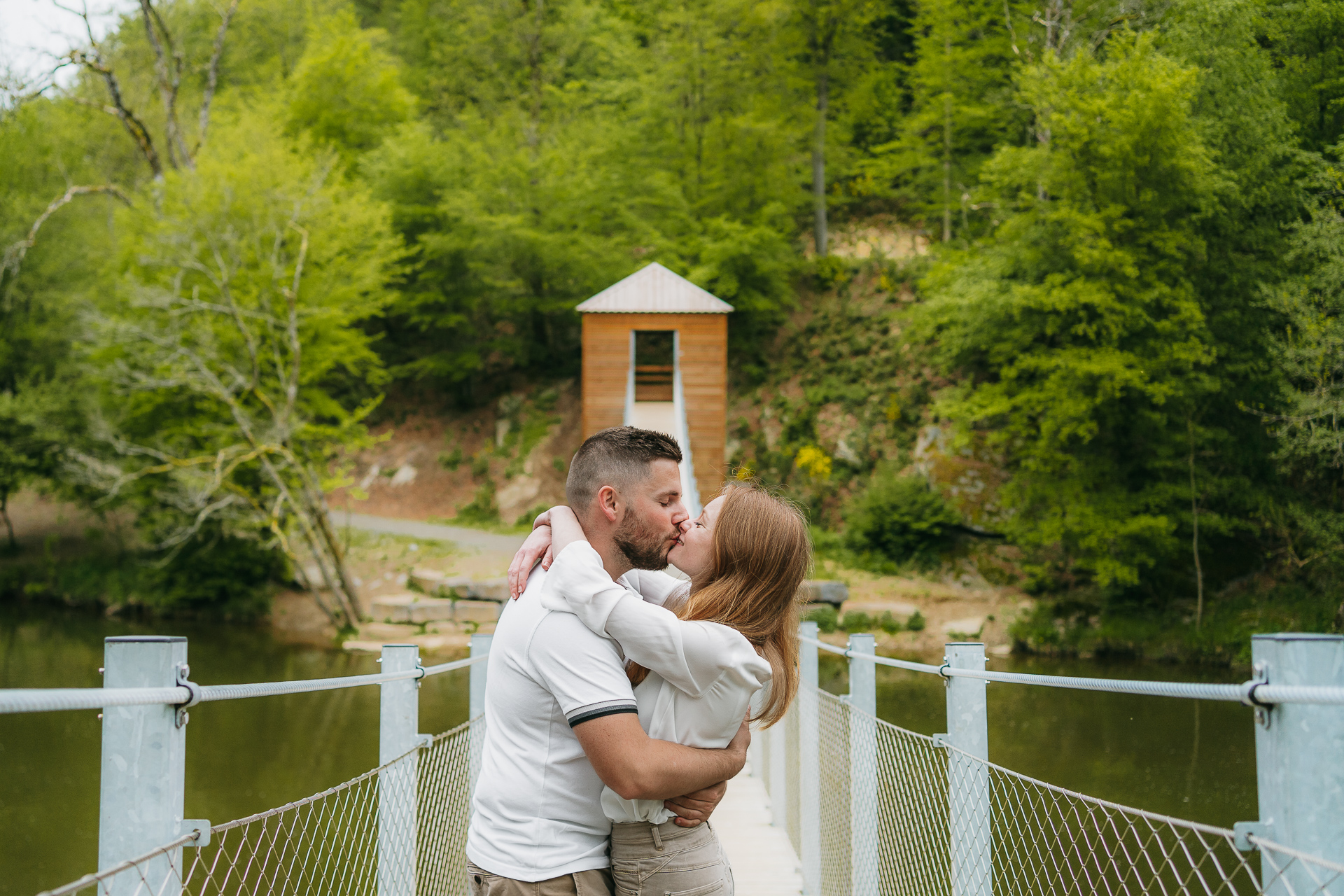 Un couple s'embrassant sur un pont au-dessus d'une rivière.
