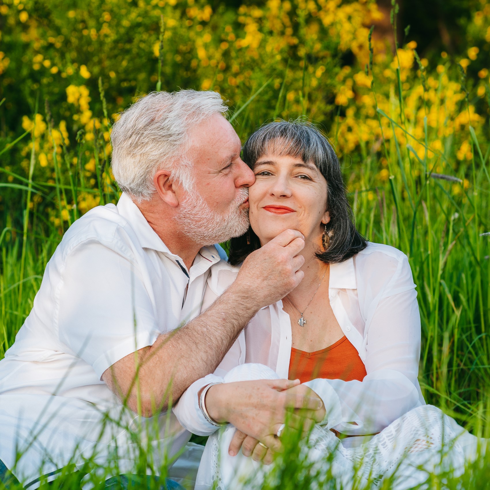 Un couple de personnes âgées s'embrassant dans l'herbe.