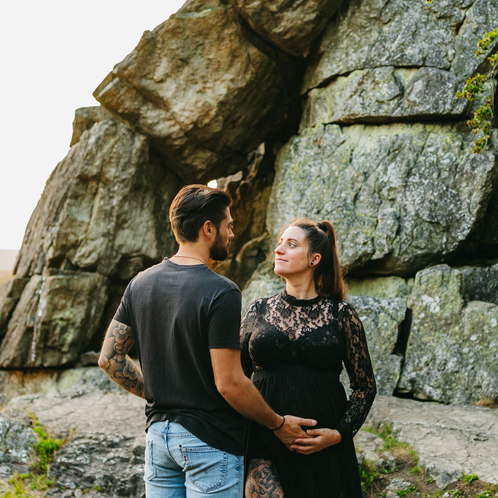 Un couple enceinte debout devant un rocher.