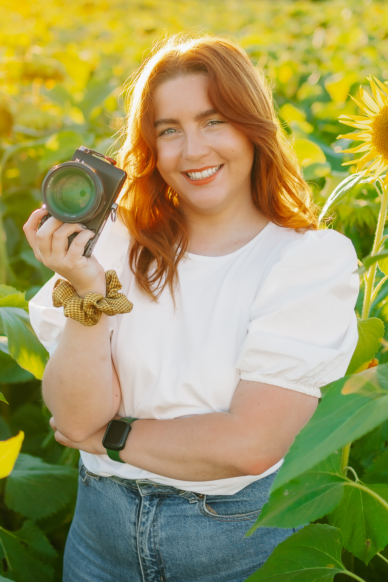 Une femme tenant un appareil photo dans un champ de tournesols.