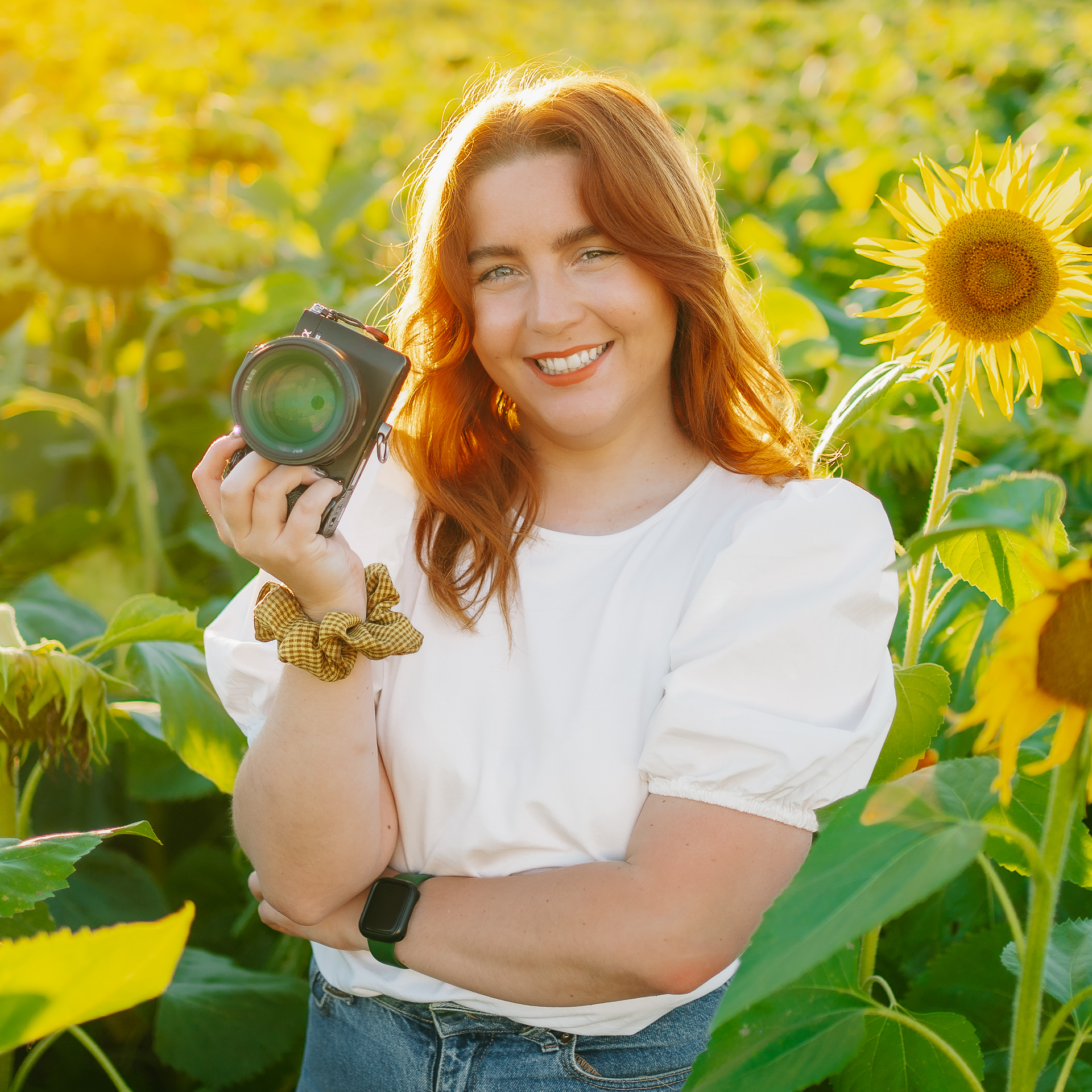 Une femme tenant un appareil photo dans un champ de tournesols.