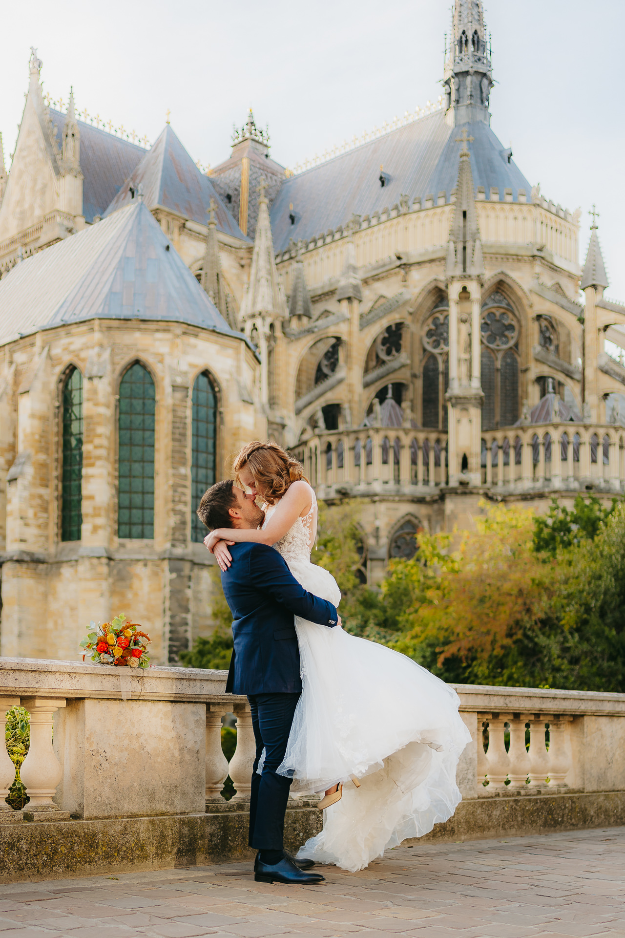 Les jeunes mariés s’embrassent devant une cathédrale historique.